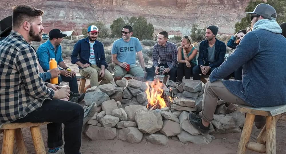 Group of people sit around a camp fire