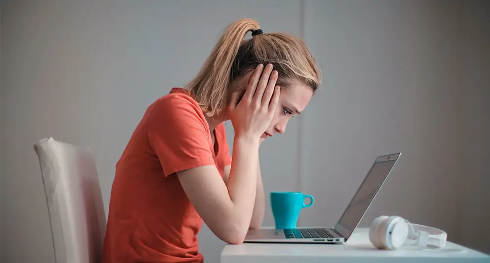 Worried-looking woman stares at laptop screen