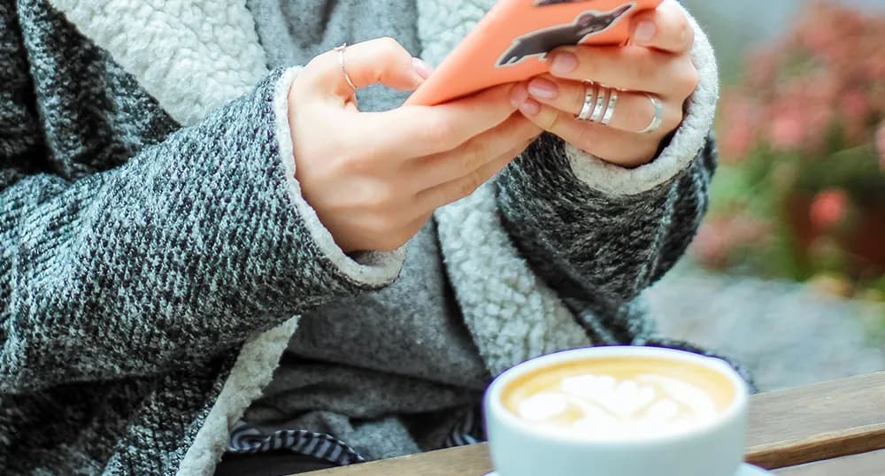 Woman with coffee types on cell phone