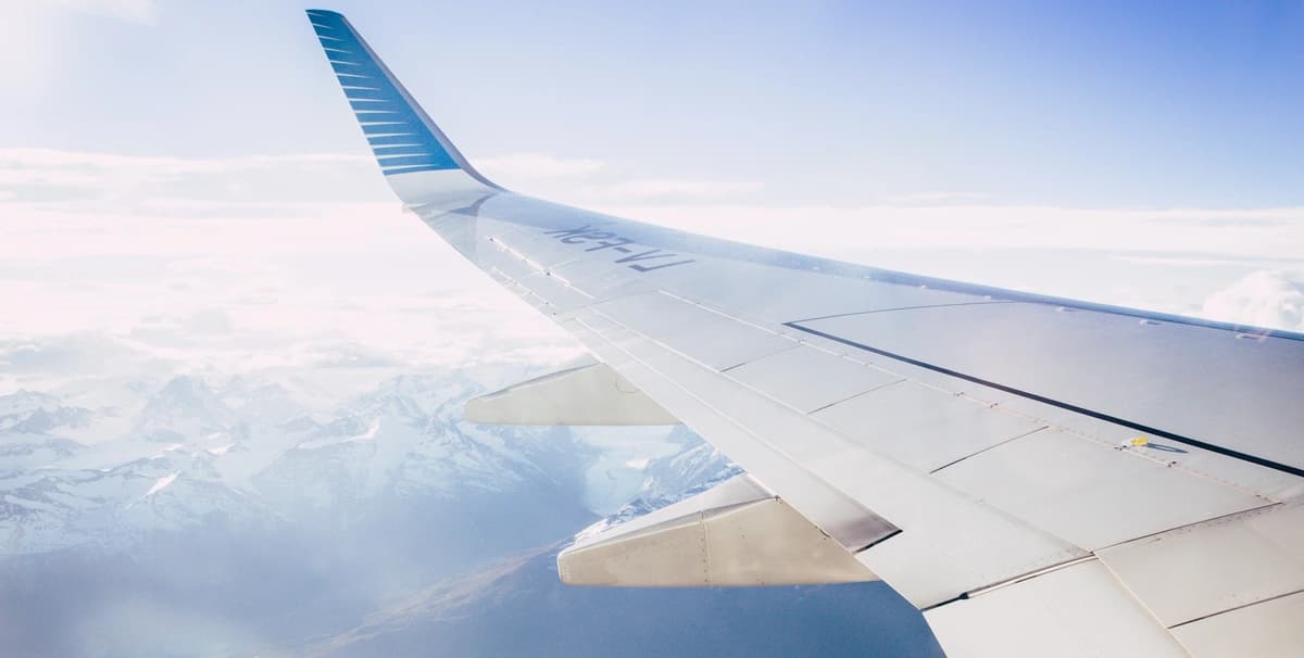 airplane wing flying over snow-capped mountains