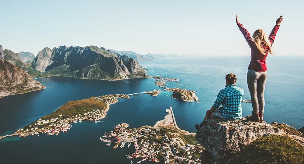 People standing on a cliffside, woman with arms raised in celebration