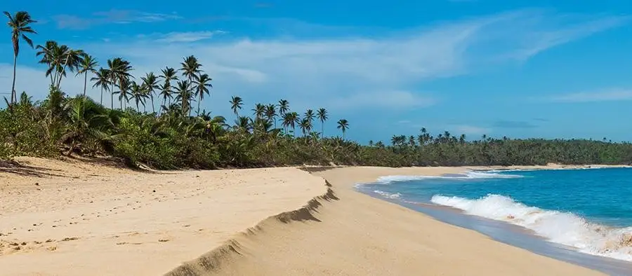 Caribbean beach with blue skies, blue water, and white sand