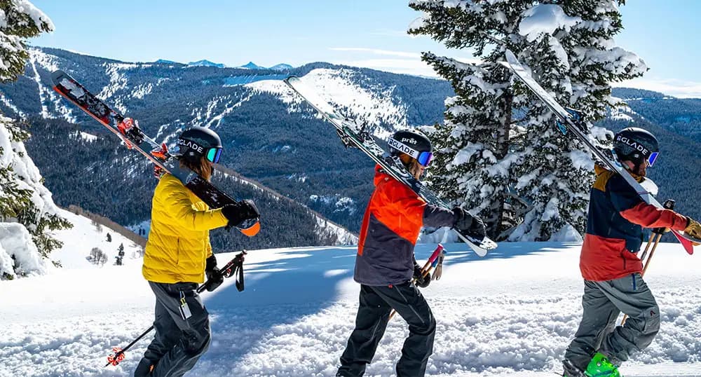 Three skiers hiking in the snowy mountains with their gear