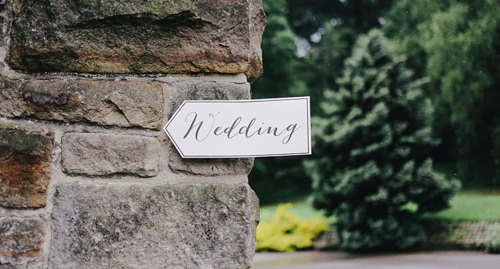 White sign pointing the way to a wedding ceremony