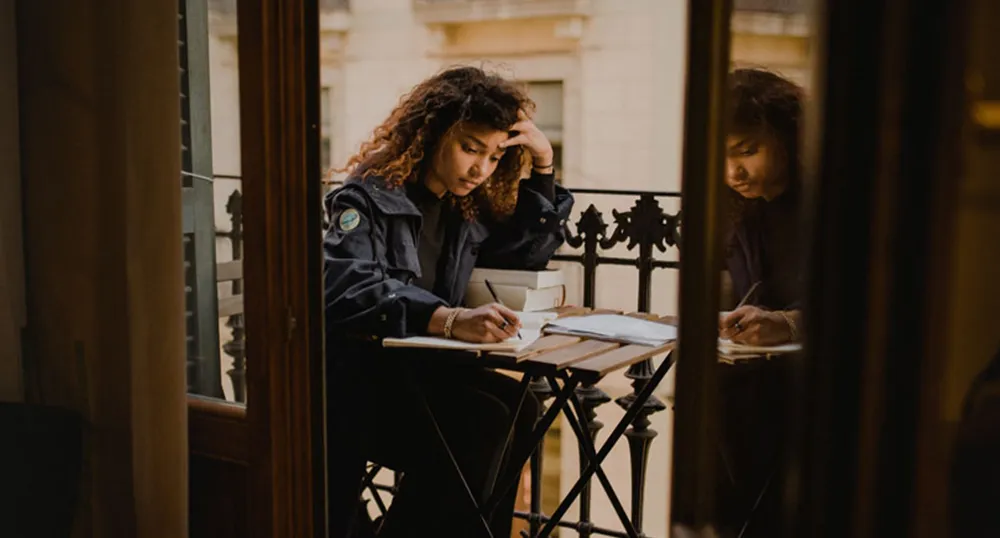 Woman studies at a small table on a balcony